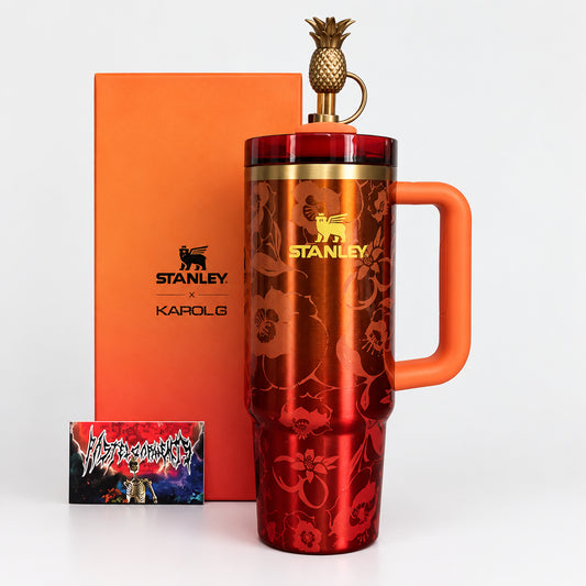 Red Stanley mug with an orange handle and pineapple spout on a wooden surface.